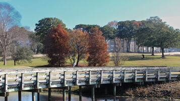 A wooden bridge over a body of water with trees and a building in the background.