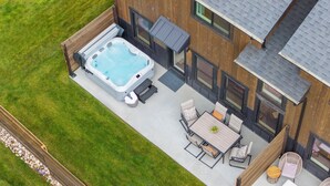 Eine Luftaufnahme eines Hauses mit Whirlpool, einer Terrasse mit Tisch und Stühlen sowie einer Holzterrasse.