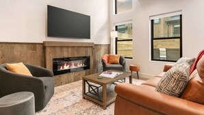 Ein modernes Wohnzimmer mit Kamin, Ledersofas, einem Couchtisch und großen Fenstern.