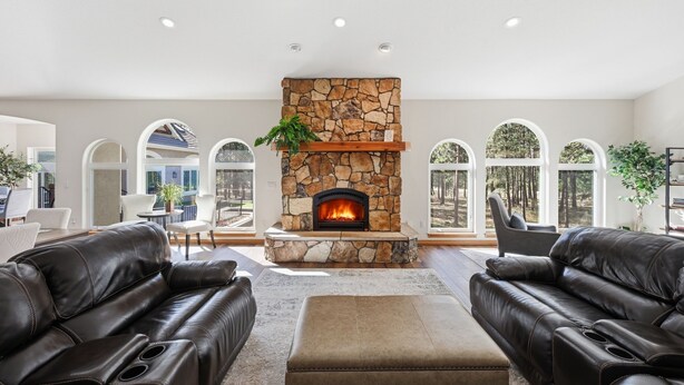 Una sala de estar con chimenea de piedra, sofás de cuero y ventanas amplias.