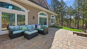 Un patio con un sofá modular, una mesita y suelo de ladrillo.
