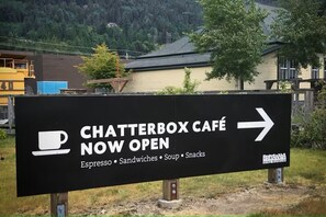 A sign for Chatterbox Café indicating it is now open, with a directional arrow.