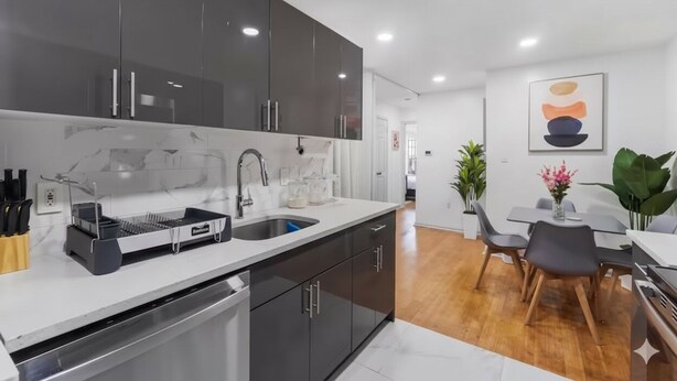 A modern kitchen with dark cabinets, a stainless steel sink, and a built-in oven.