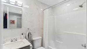 A modern bathroom with a white sink, mirror, and toilet.