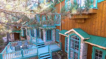 A multi-level wooden house with stone walls and turquoise accents, featuring multiple balconies and windows.