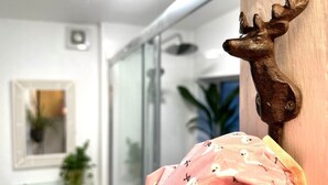 A bathroom with a shower, a mirror, and a decorative deer head.
