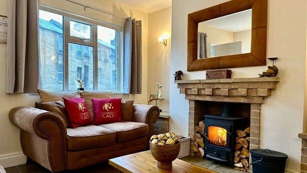 A cozy living room with a fireplace, a sofa with red pillows, and a wooden table.