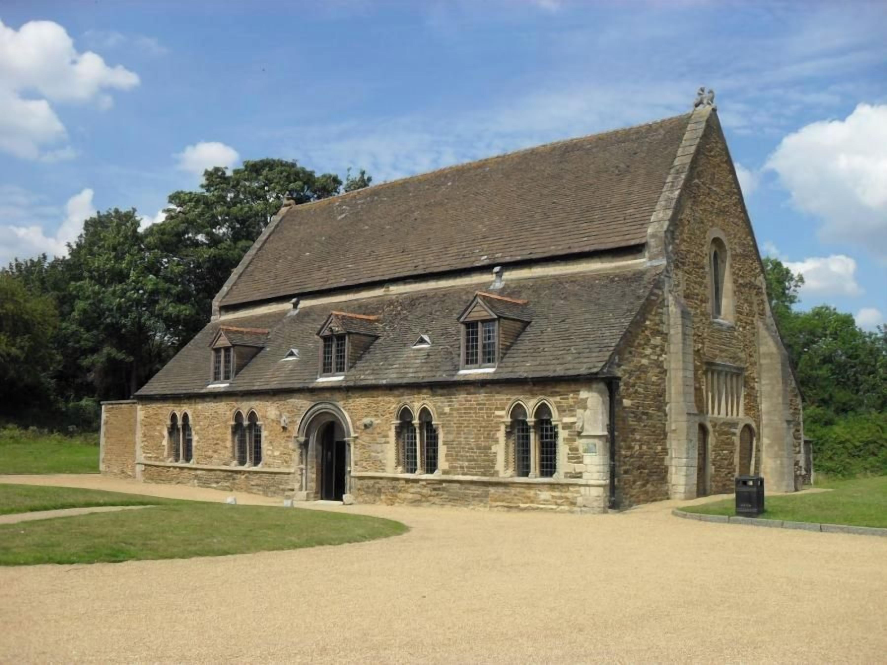 A stone building with a pitched roof, arched windows, and a small tower.