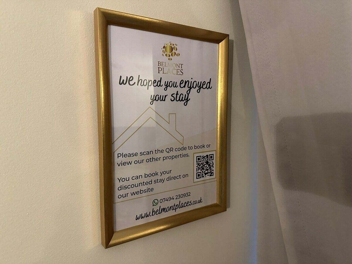 Ein gerahmtes Schild mit einem QR-Code, dem Hotel-Logo und der Aufforderung an Gäste, Zimmer zu buchen oder andere Objekte anzusehen.
