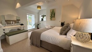 Ein Schlafzimmer mit Bett, Nachttisch, Schminktisch und Fenster.