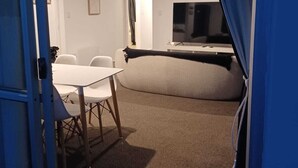 A room with a bed, a TV, a table with chairs, and a door.