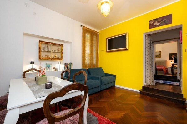 Uma sala de jantar com uma mesa branca, cadeiras de madeira e um tapete vermelho.