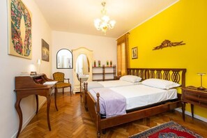Quarto com cama de madeira, escrivaninha, cadeira, espelho e lustre.