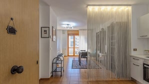 A modern kitchen with a dining area, a wooden door with a coat hook, and a patterned rug. - Andrea's home Bari (Bari)