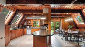 A spacious kitchen with a central island, wooden ceiling beams, and large windows. - Rustic A Frame Cabin. Nature retreat on 4 acres! 15 minutes from 3 waterfalls (LaFayette)