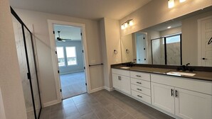 Une salle de bain moderne avec un grand meuble-lavabo, un miroir et un ventilateur de plafond.