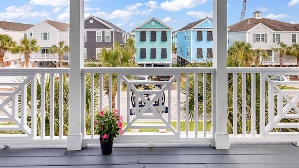 A porch with a view of colorful houses and palm trees.