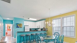 A kitchen with white cabinets, a bar area with stools, and a dining table with chairs.