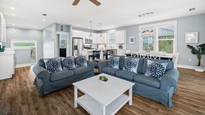 Ein modernes Wohnzimmer mit einem grauen Ecksofa, einem weißen Couchtisch und einem Deckenventilator.