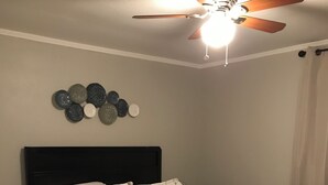 A bedroom with a bed, a ceiling fan, and wall decor. - 3-bedroom house in charming Magnolia with AC (Magnolia)