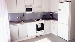 A modern kitchen with white cabinets, a microwave, stove, and refrigerator.