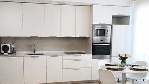 Una cucina moderna con mobili bianchi, forno integrato e zona pranzo con tavolo e sedie rotonde.