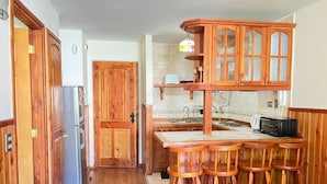 A kitchen with wooden cabinets, a refrigerator, a sink, and a toaster. - Volcano shelter. 1 km from downtown! (Araucanía)