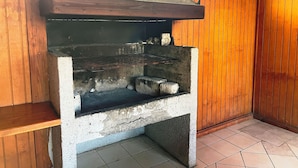 A concrete outdoor grill with a metal hood, set against a wooden wall. - Volcano shelter. 1 km from downtown! (Araucanía)
