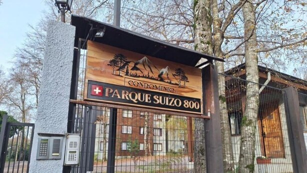 A gated entrance to a residential complex named "Parque Suizo 800" with a signboard featuring a mountain and trees. - Volcano shelter. 1 km from downtown! (Araucanía)