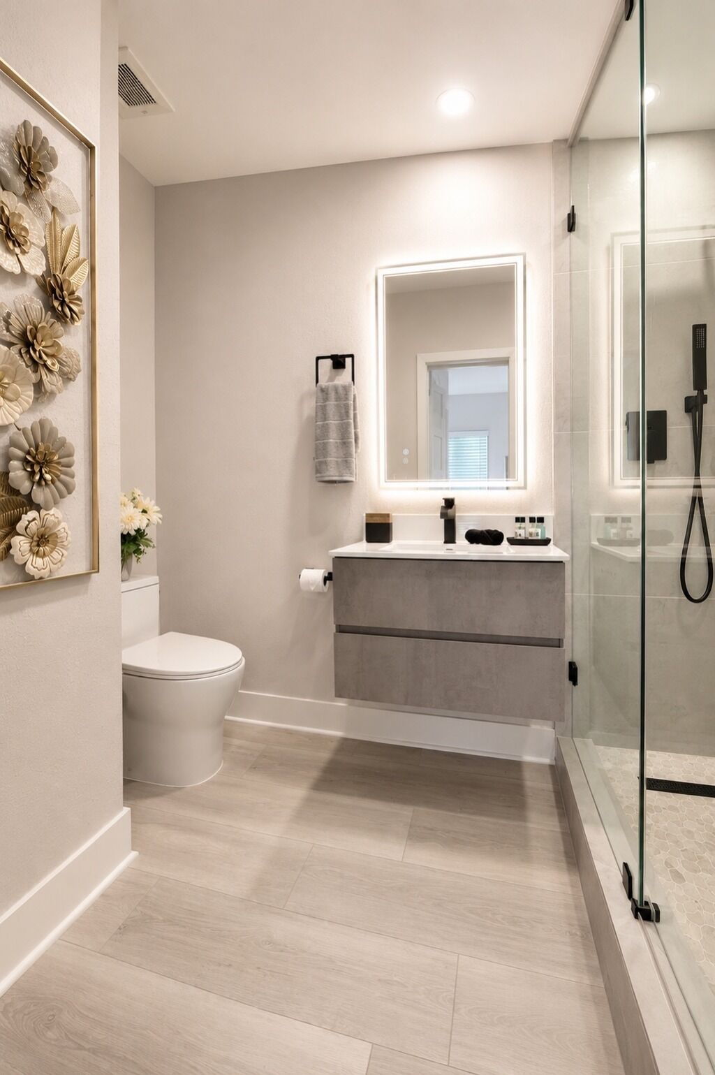 A modern bathroom with a toilet, vanity, and glass shower enclosure.