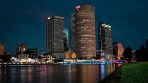 Un horizonte urbano con edificios modernos altos, un muelle y un puente con luces de colores.