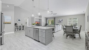 A modern kitchen with a central island, built-in appliances, and pendant lighting. - Newly Remodeled, Spacious 4-Bedroom Getaway (Palm Coast)