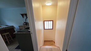 A narrow hallway with a wooden floor, a small window, and a ceiling light.