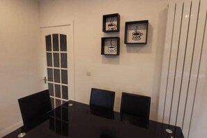 A conference room with a glass table and black chairs, framed coffee cup artwork on the wall, and a door with frosted glass panels.