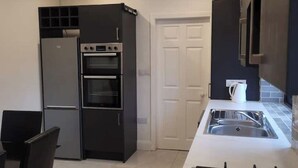 Une cuisine de taille réduite équipée d’un réfrigérateur, d’un four et d’un évier.