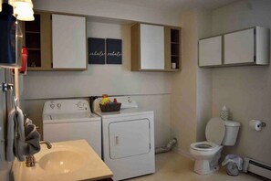 Ein kleines Badezimmer mit Waschbecken, Toilette und Waschmaschine.