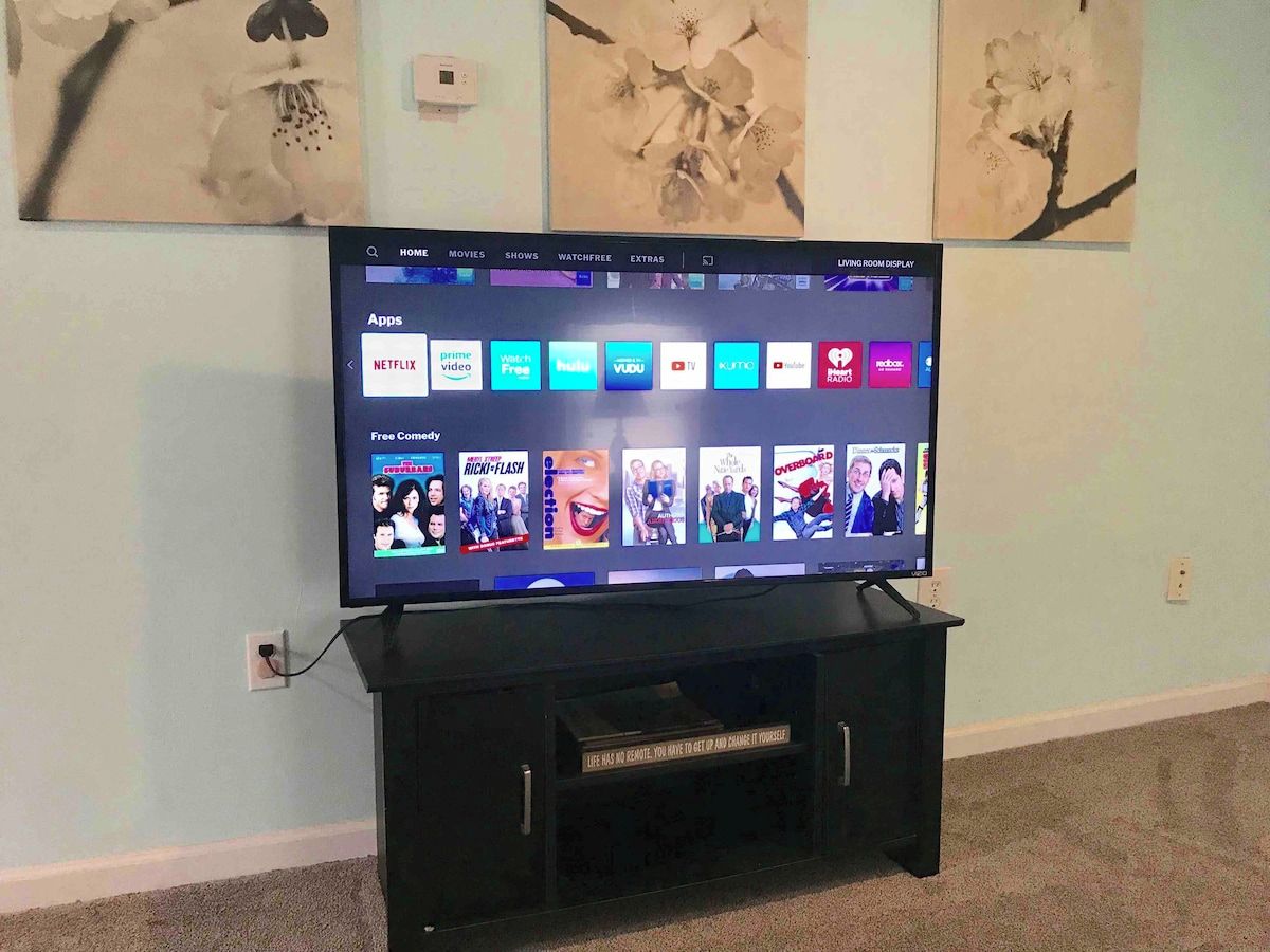 Een televisie op een zwart voetstuk, met een menu dat verschillende streaming apps toont.