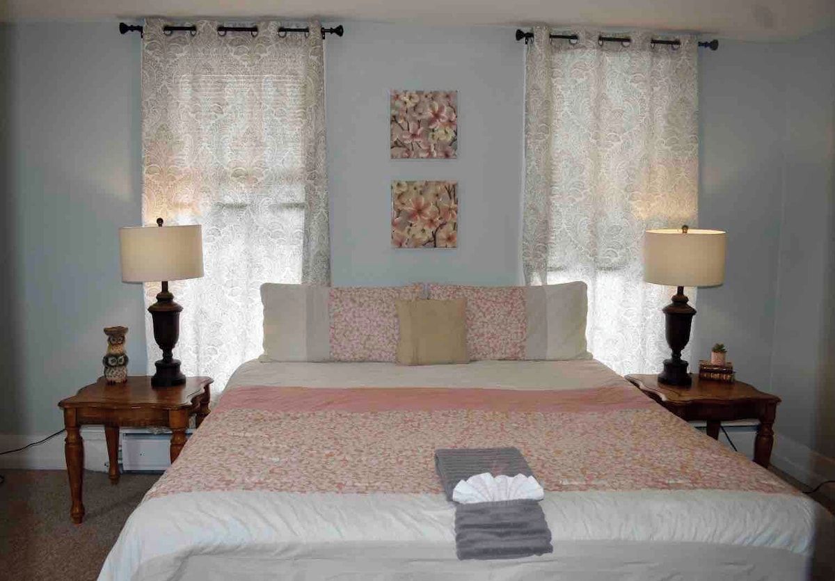 A bedroom with a large bed, two bedside tables, and curtains.