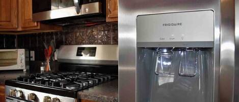 A kitchen with a stainless steel stove, a microwave, and a water dispenser.