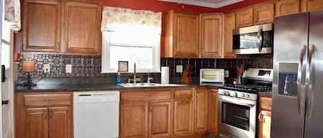 A kitchen with wooden cabinets, a dishwasher, a stove, a microwave, and a refrigerator.