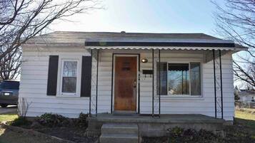A single-story house with a front porch, a wooden door, and a small front yard.