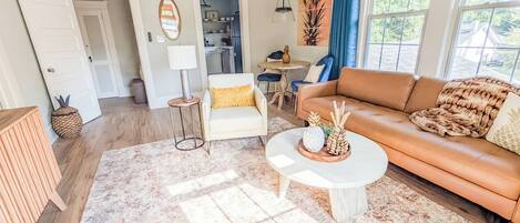A living room with a sofa, coffee table, and a dining area with a table and chairs.
