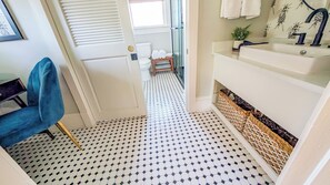 A narrow hallway with a patterned floor leading to a bathroom with a white sink and a blue chair. - Boutique Private Apt Walk to Downtown Florence (Florence)
