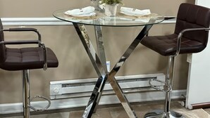 A glass-top table with two chairs, a potted plant, and a vase. - Cozy private one bedroom basement apartment with private parking and entrance. (Landover)