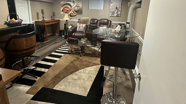 A spacious living room with a large black and white rug, leather chairs, a glass coffee table, and a fireplace. - Cozy private one bedroom basement apartment with private parking and entrance. (Landover)