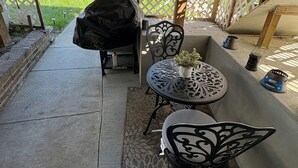 A covered patio area with a table and chairs, a barbecue grill, and a decorative fence. - Cozy private one bedroom basement apartment with private parking and entrance. (Landover)