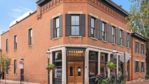 A corner brick building with a storefront, large windows, and a decorative entrance. - Wellness Retreat - Hot Tub • Sauna • Fire Pit • Outdoor TV (Columbus)
