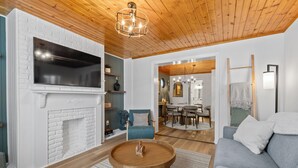 A modern living room with a fireplace, a television, and a dining area. - Wellness Retreat - Hot Tub • Sauna • Fire Pit • Outdoor TV (Columbus)