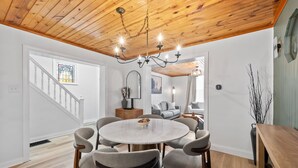 A dining area with a round table, six chairs, a chandelier, and a wooden ceiling. - Wellness Retreat - Hot Tub • Sauna • Fire Pit • Outdoor TV (Columbus)