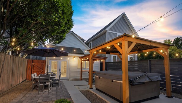 A backyard with a wooden pergola, outdoor seating, and string lights. - Wellness Retreat - Hot Tub • Sauna • Fire Pit • Outdoor TV (Columbus)
